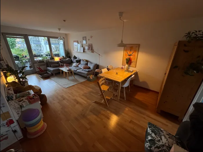 The original phone photo: a lived-in room with a grey sofa, dining table, plants and toys.
